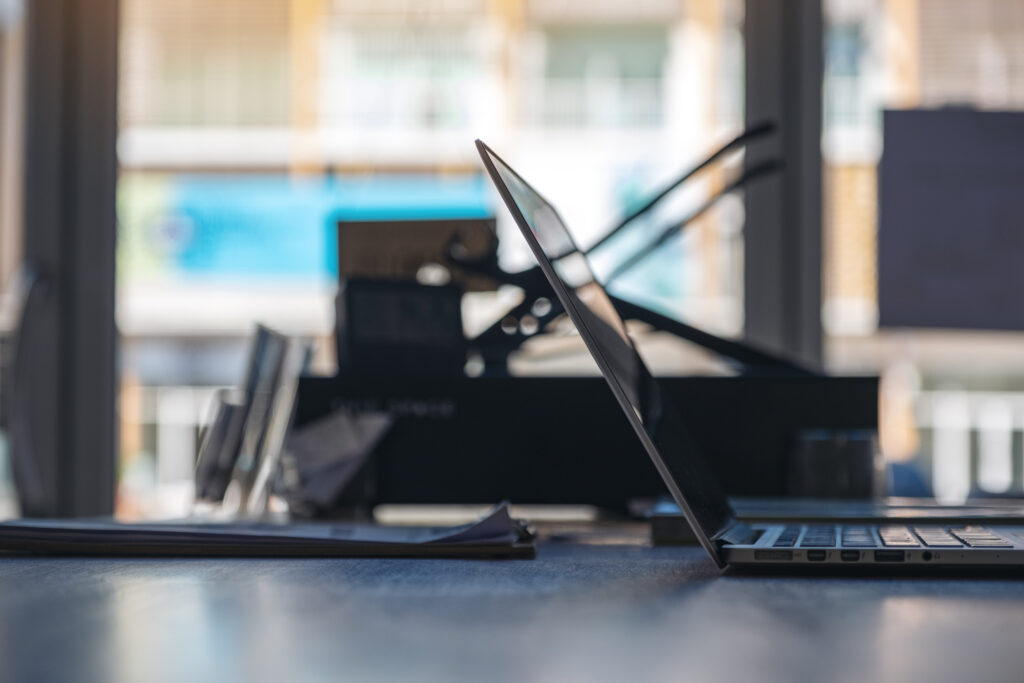 sleek pen resting on top of a signed legal contract or document next to a modern laptop/tablet on a minimalist office desk